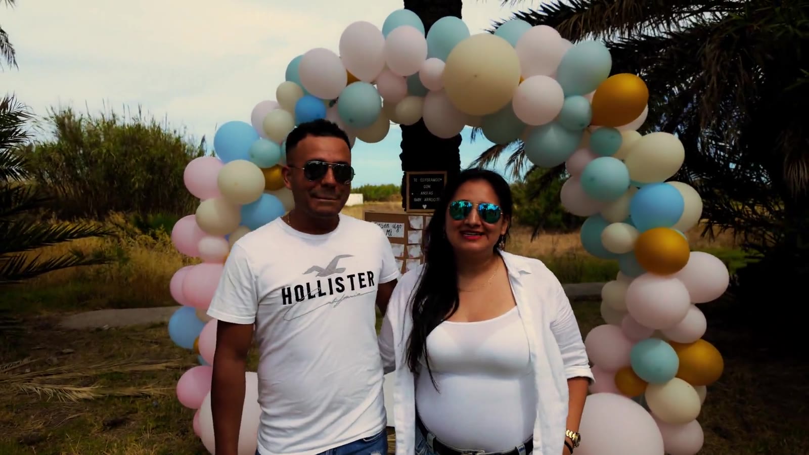 A couple beneath a pastel balloon arch