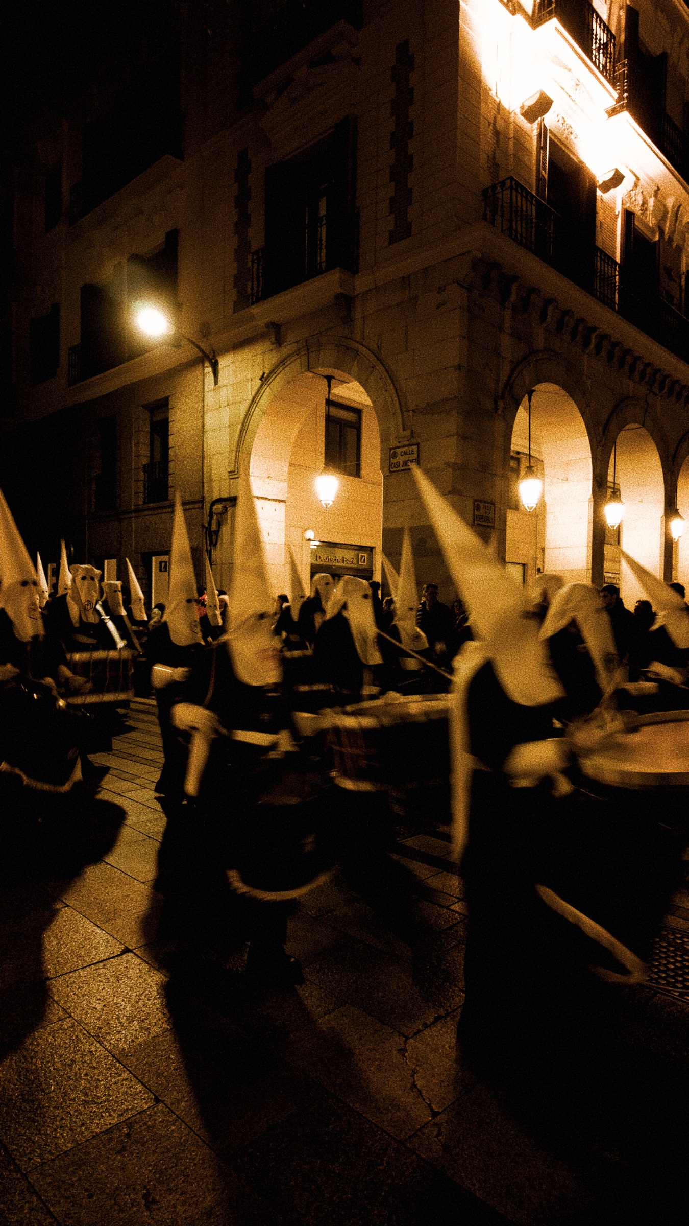 Good Friday procession moving through an amber-lit street in Zaragoza